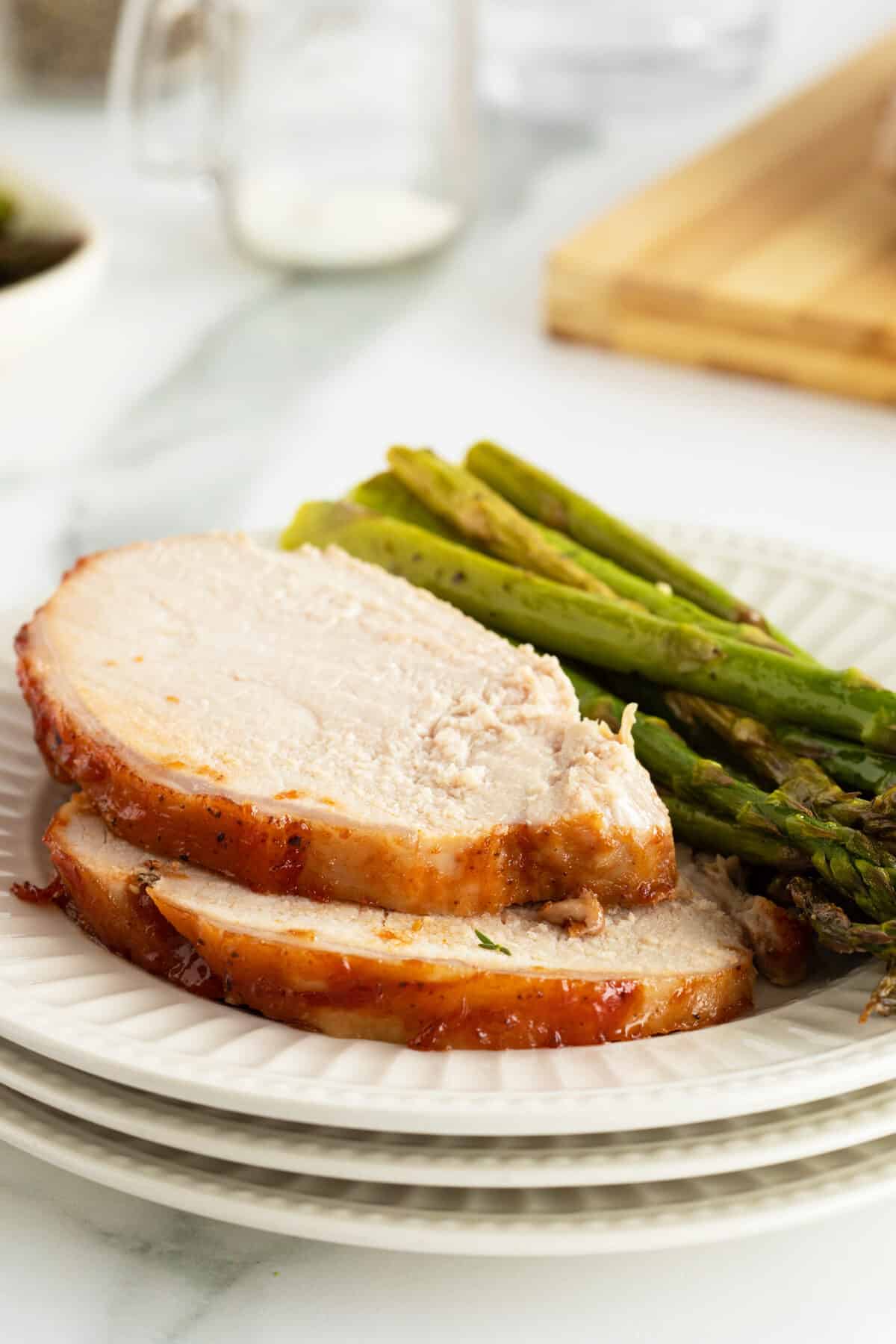 Grilled pork loin slices on a white plate with asparagus on the side