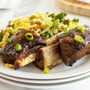 beer glazed beef ribs on a white plate with a salad