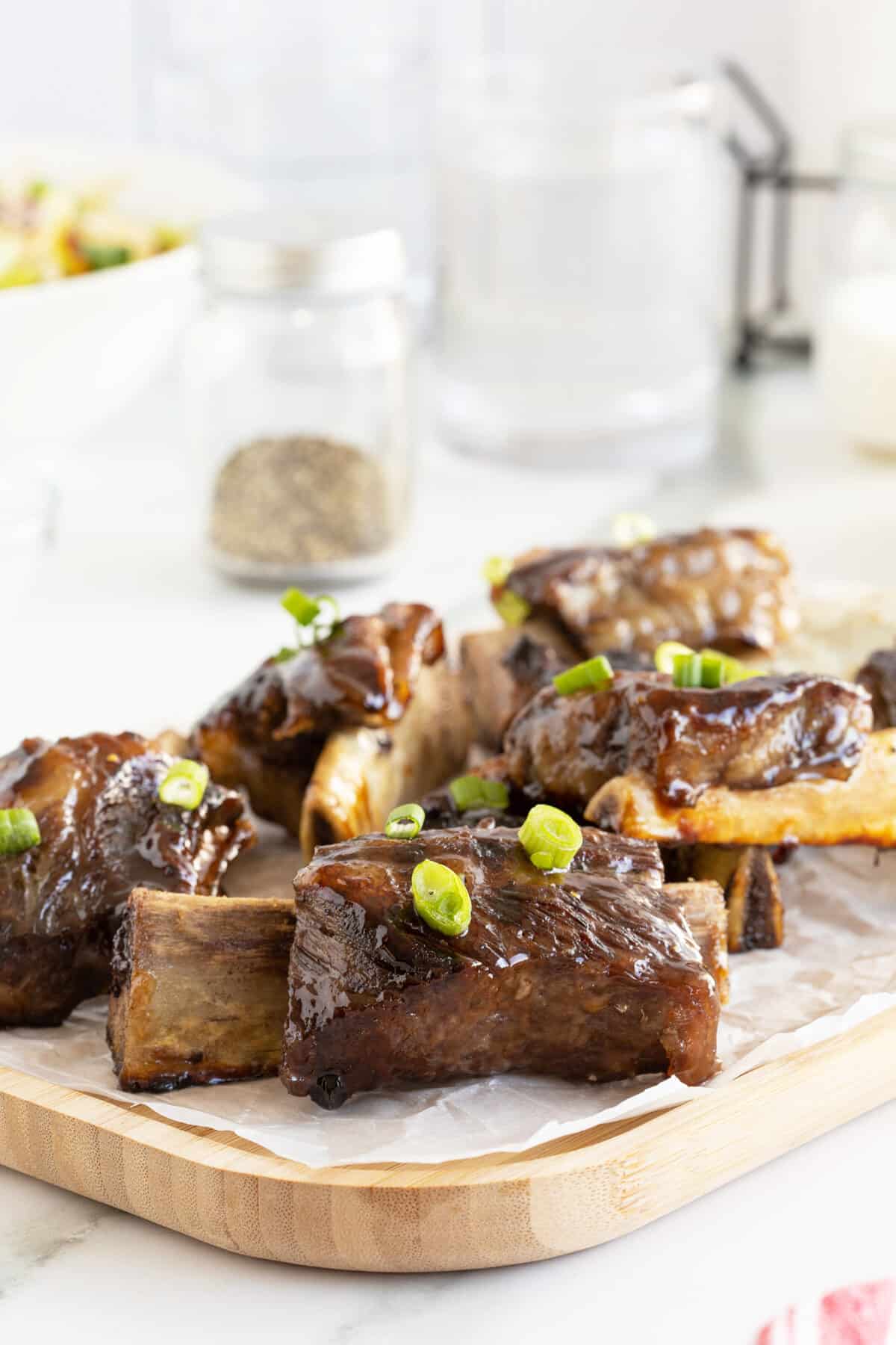 beer glazed beef ribs on a cutting board with green onions