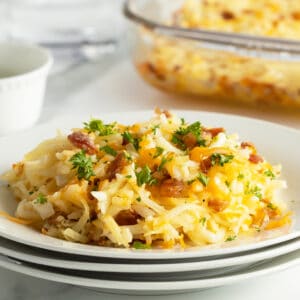 cheesy hashbrown casserole slice on a stack of white plates