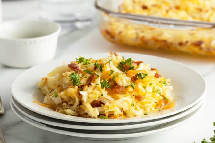 cheesy hashbrown casserole slice on a stack of white plates