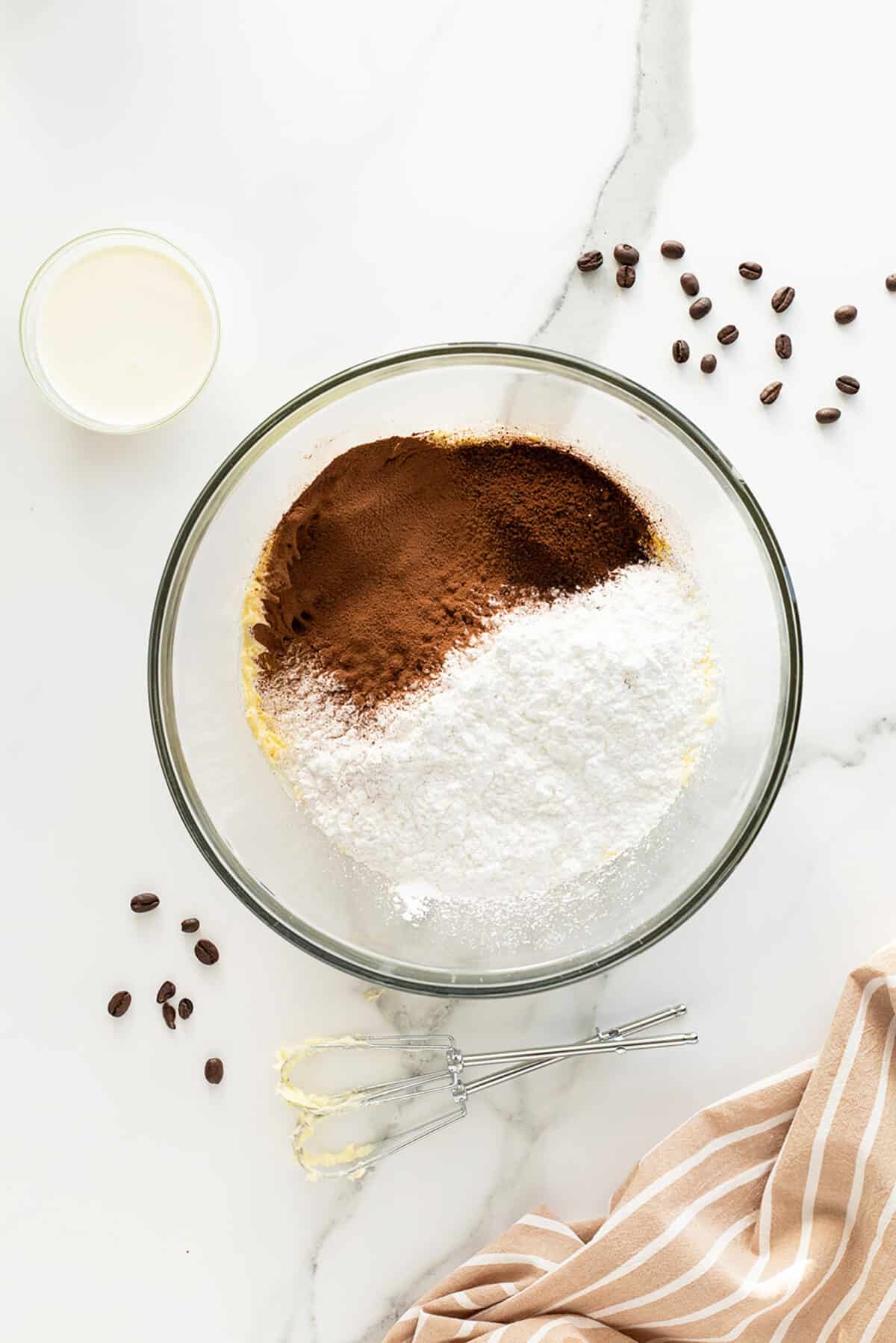 Coffee buttercream icing powdered ingredients in a clear mixing bowl