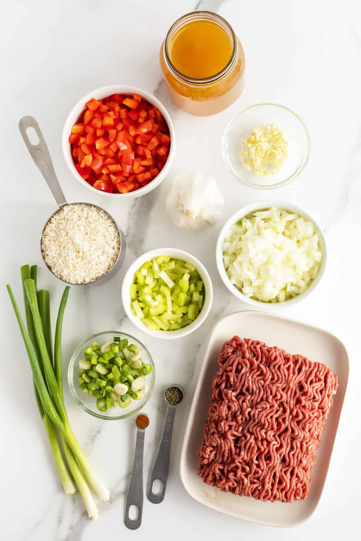 dirty rice ingredients in small white bowls and green onions 