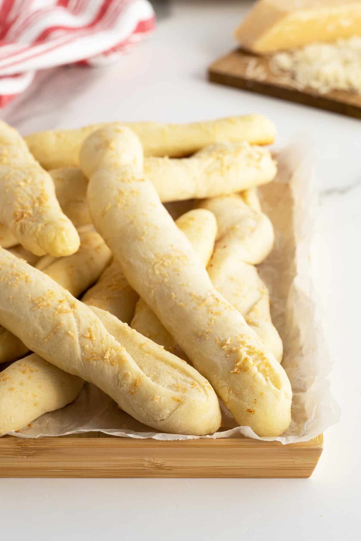 homemade breadsticks on parchment paper on a wooden cutting board
