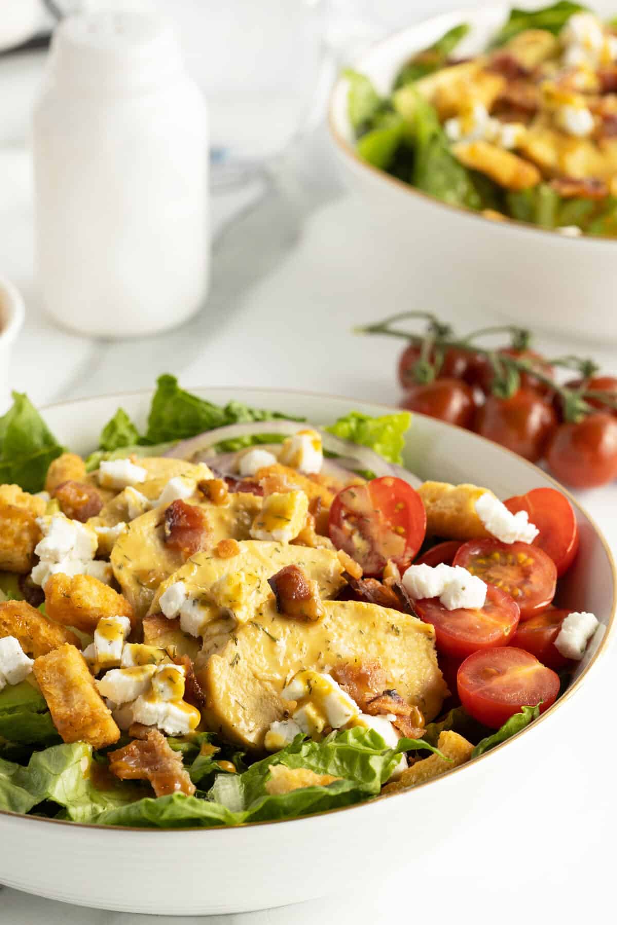 honey mustard chicken salad in a large white bowl with a bunch of cherry tomatoes to the side
