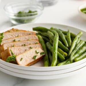 Kentucky bourbon grilled pork chops on a white plate with green beanns