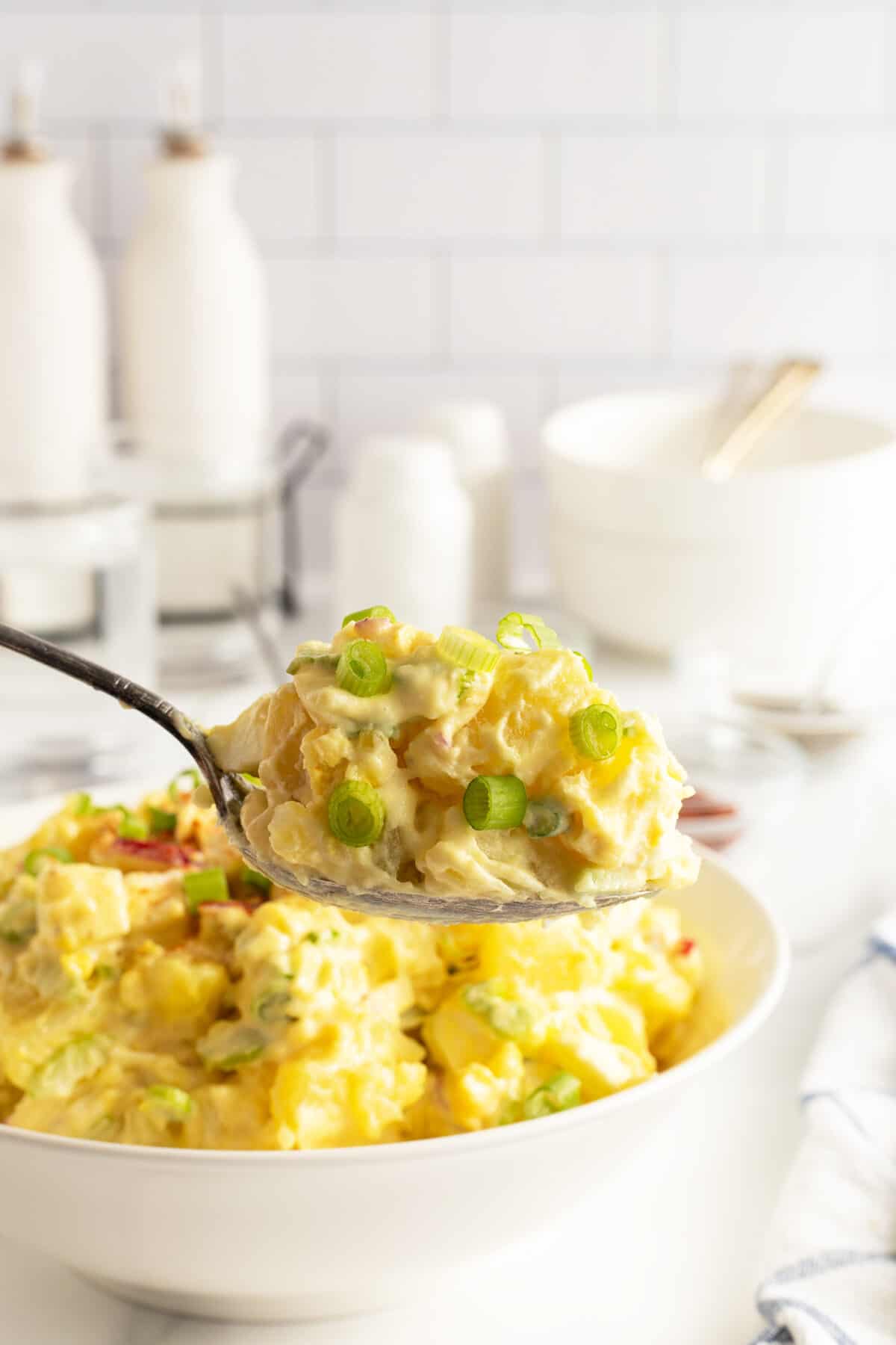 mom's potato salad lifted over a bowl on a large spoon