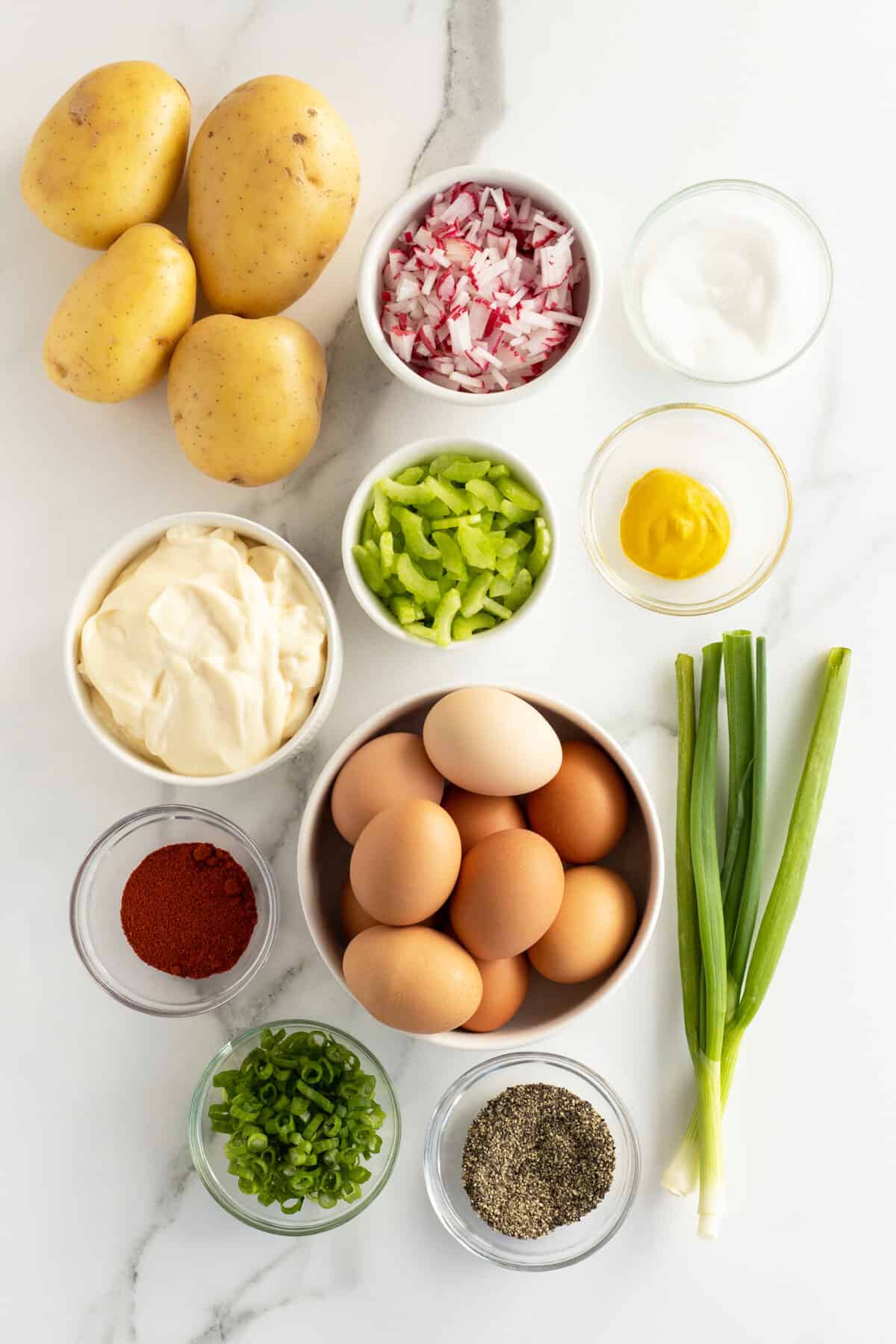 mom's potato salad ingredients in small white and clear bowls