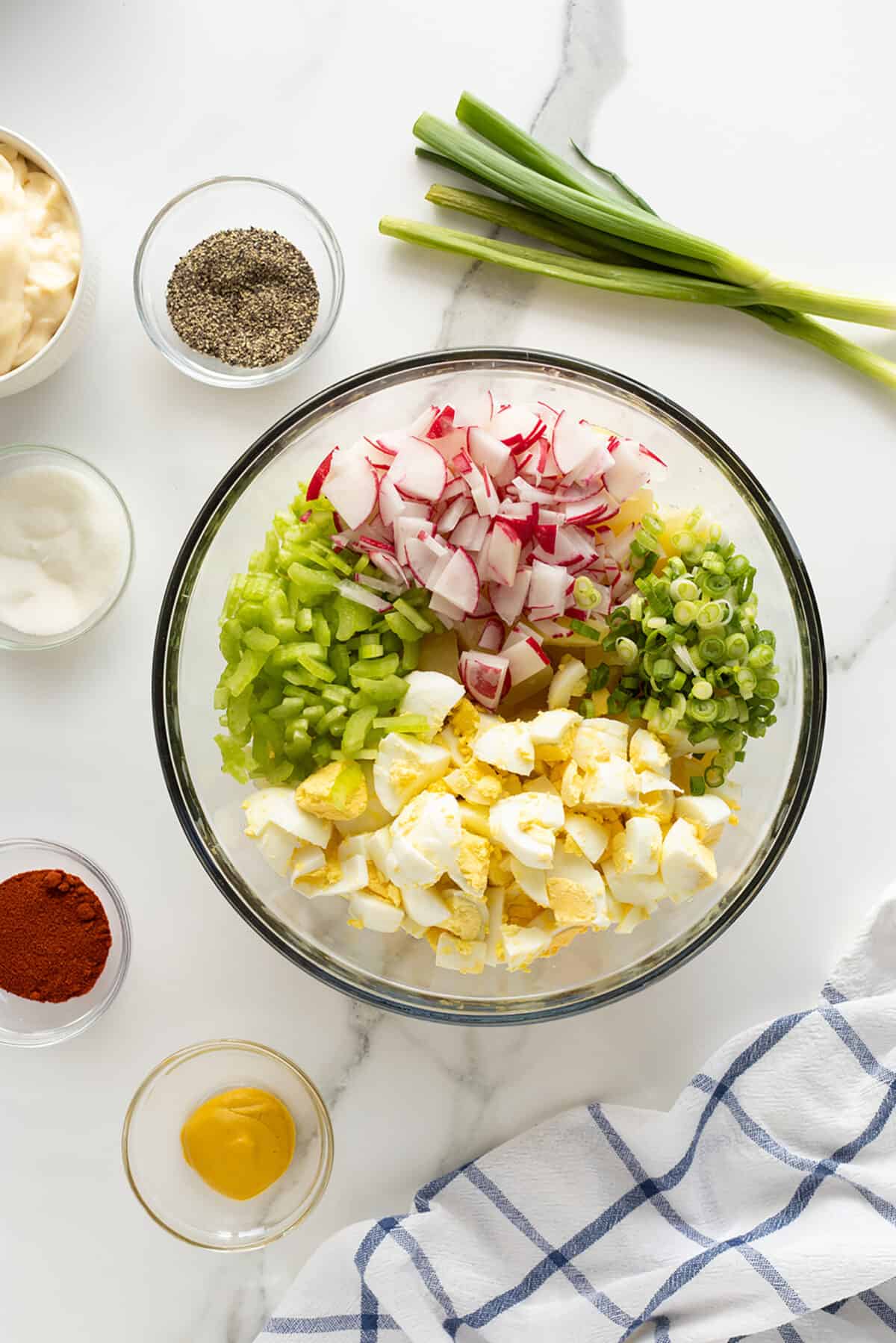 mom's potato salad ingredients in a large clear bowl un stirred