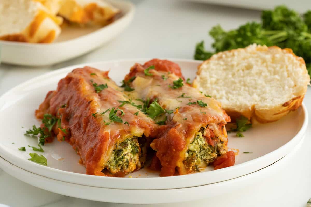 sausage stuffed manicotti On a plate with a slice of bread