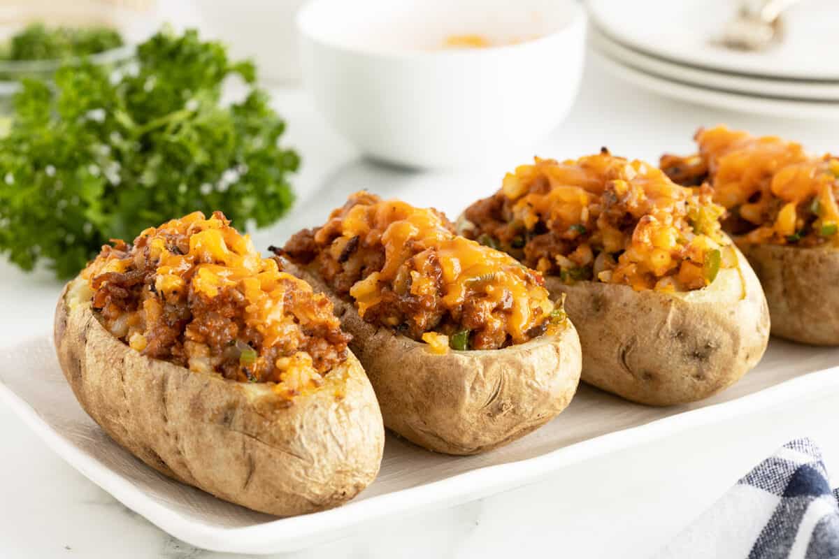 sausage stuffed potatoes lined up on a white plate