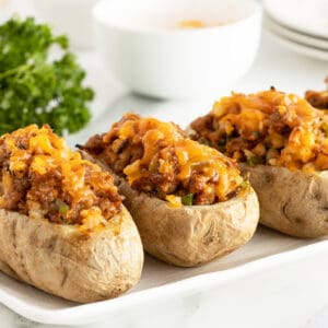 sausage stuffed potatoes lined up on a white plate