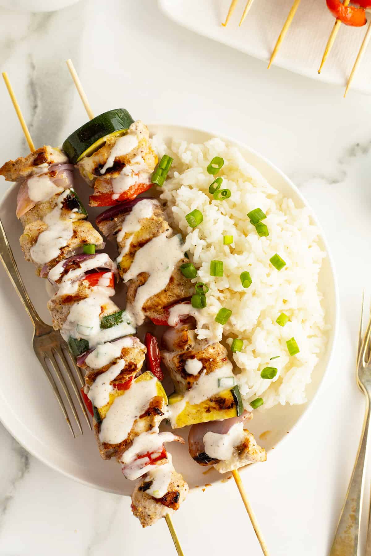 turkey kebabs on a white plate with rice