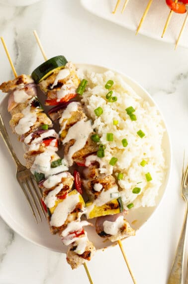 turkey kebabs on a white plate with rice