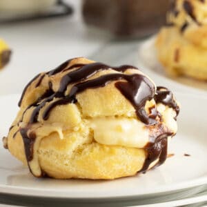 banana cream puff on a white plate with chocolate drizzle