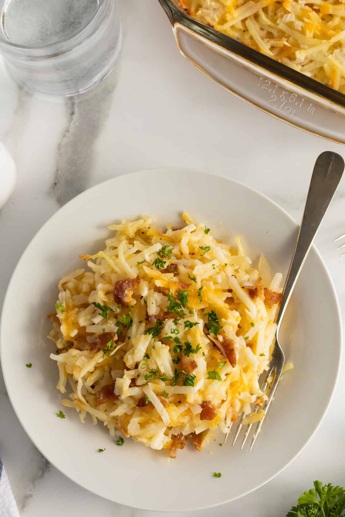 cheesy hash brown casserole  slice on a white plate with a fork