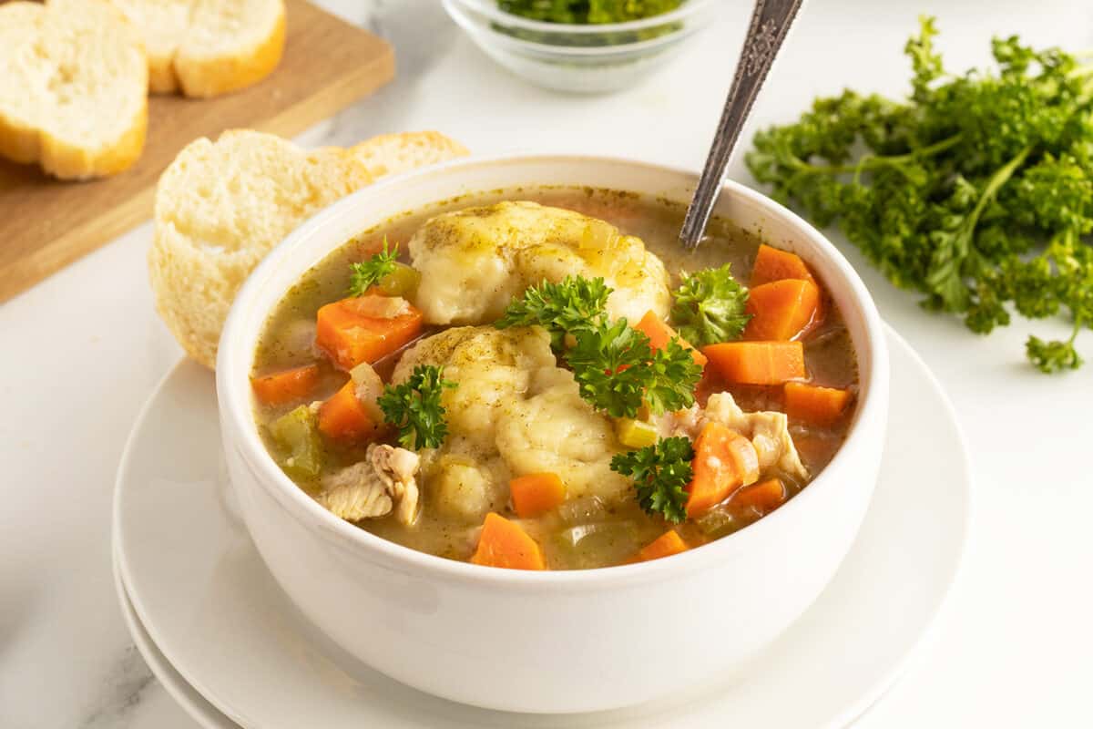 chicken and dumpling soup in a white bowl with a spoon in it