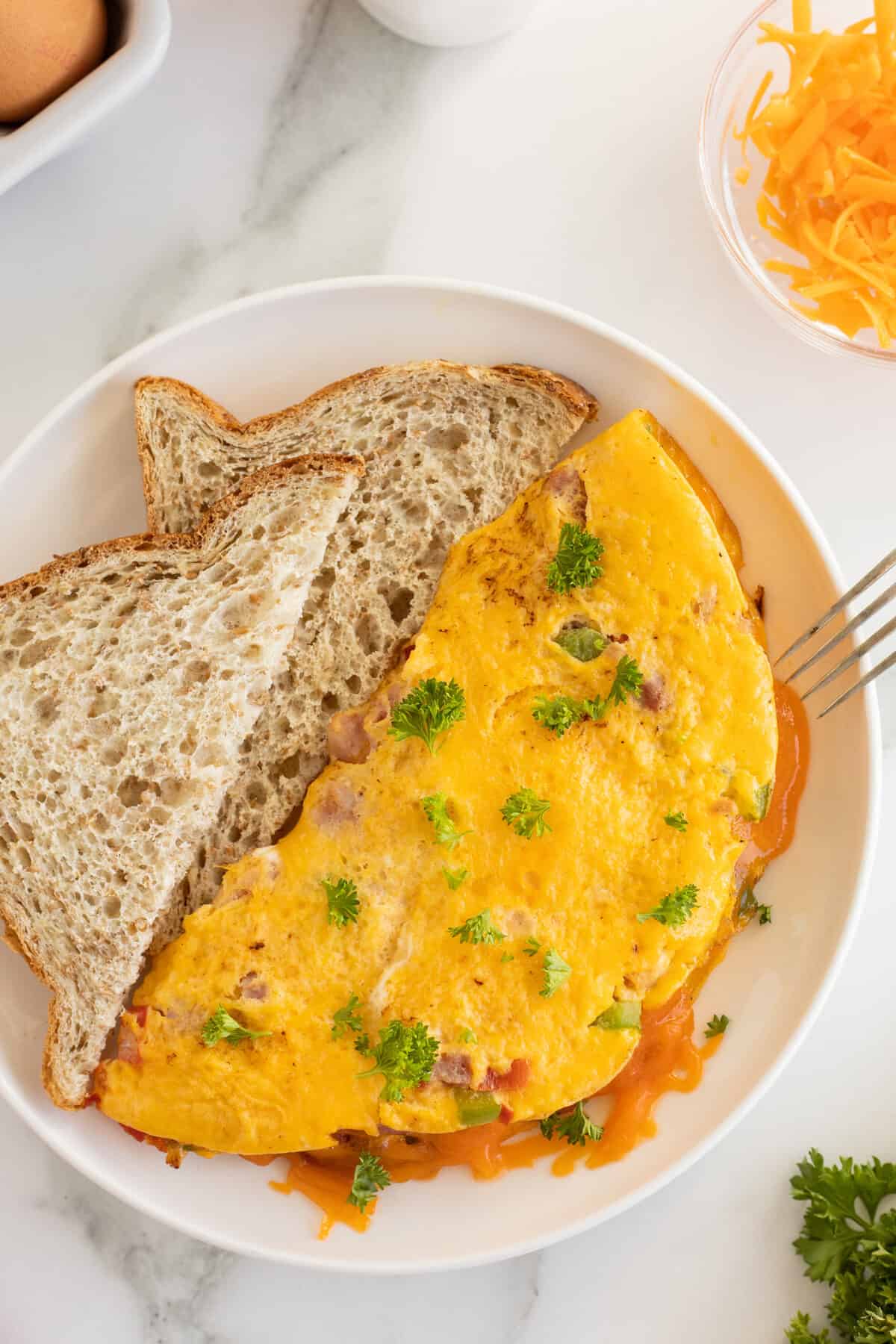 an omelet with a slice of brown bread on the side of a white plate