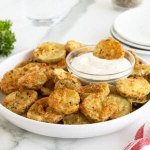 Fried Pickles on a white plate with a small bowl of dip