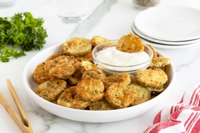 Fried Pickles on a white plate with a small bowl of dip