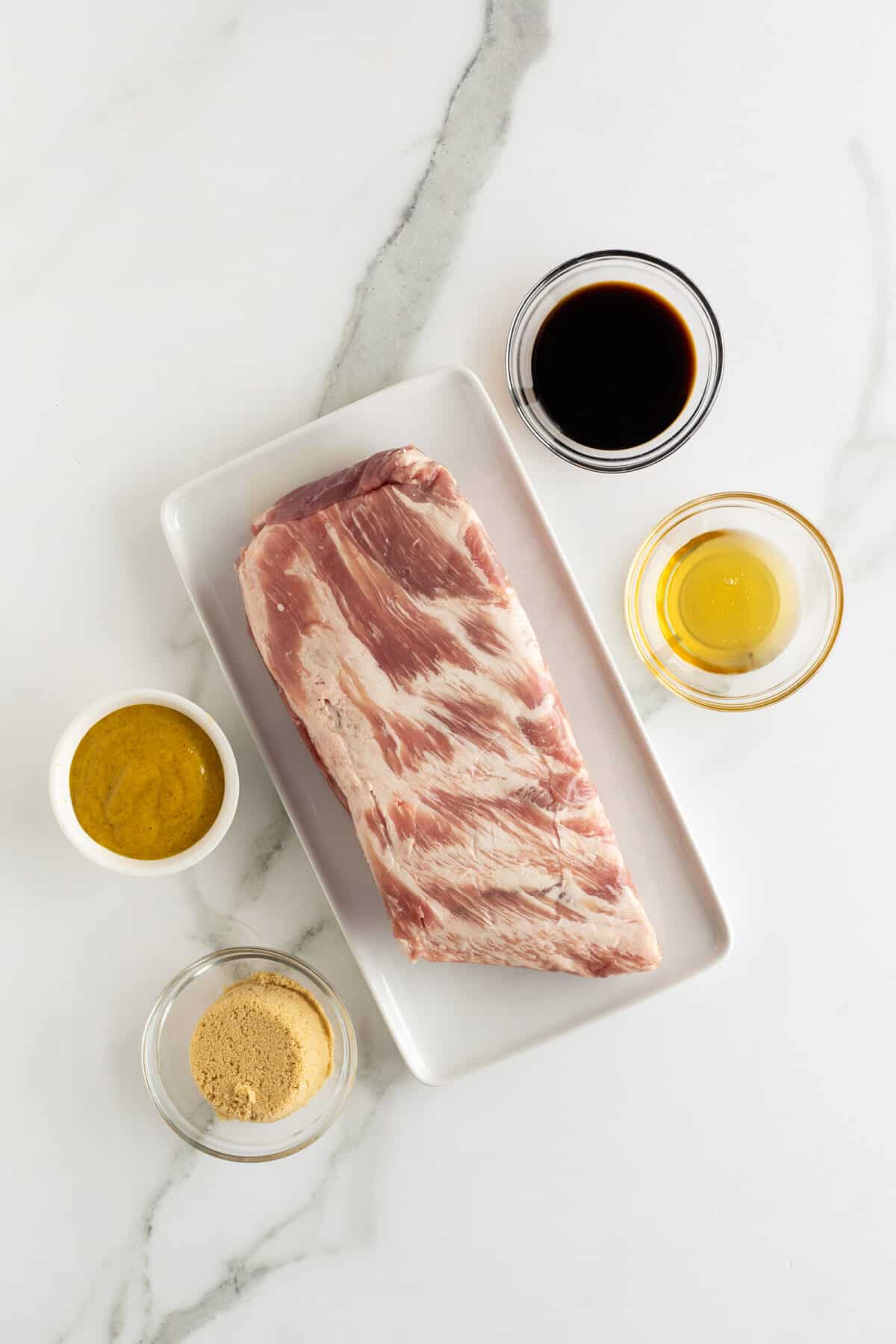 honey mustard glazed ribs ingredients in small clear bowls beside a rack of raw ribs