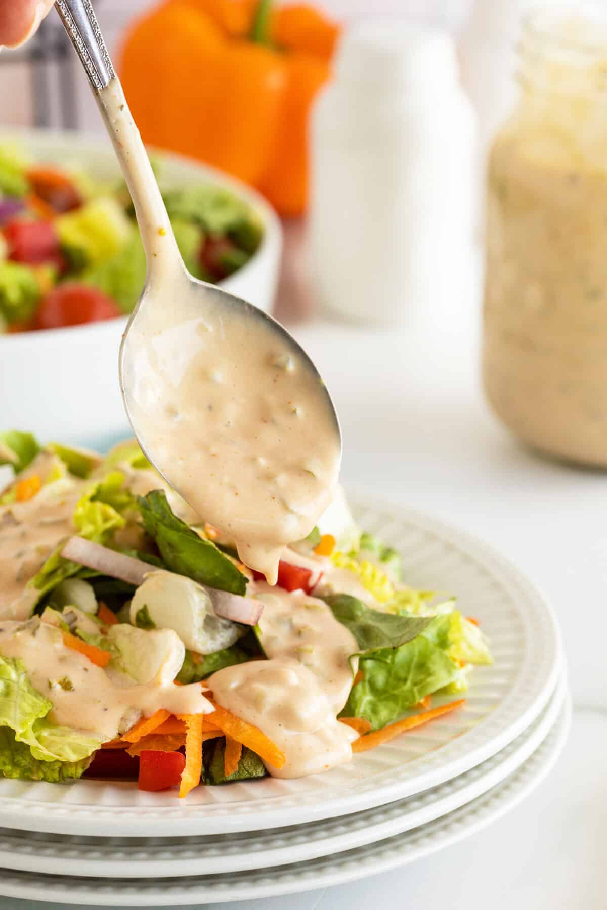 thousand island dressing dripping off a spoon onto a salad