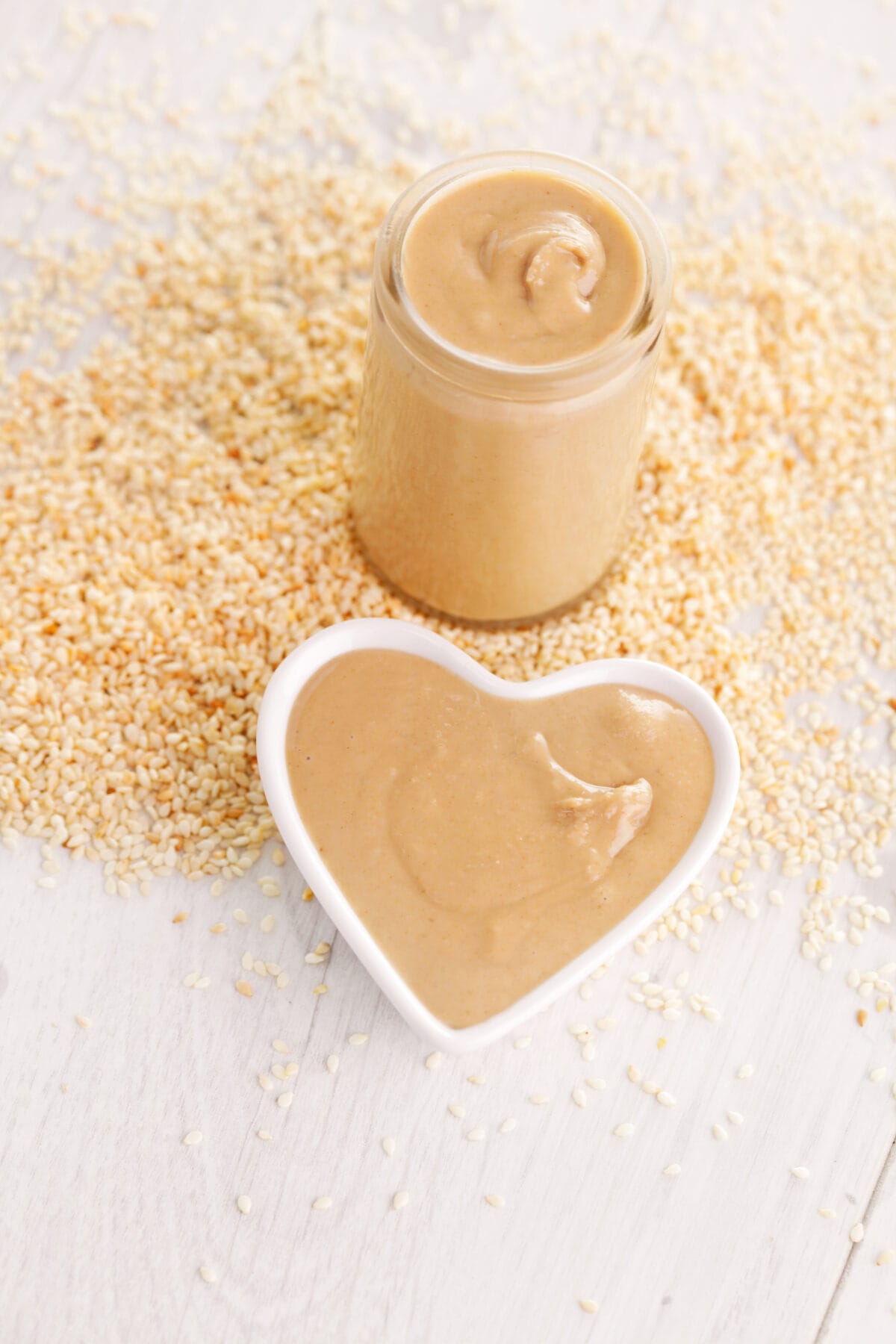 a clear jar and a heart shaped dish full of tahini paste
