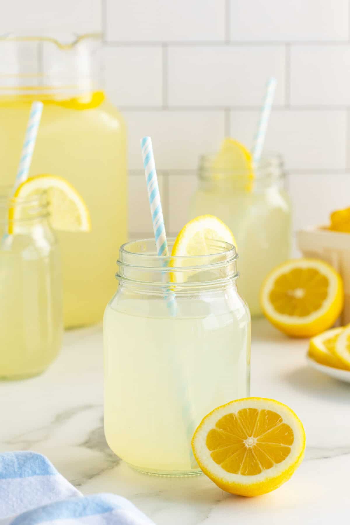 fresh lemonade in a [mason jar with a straw and slice of lemon
