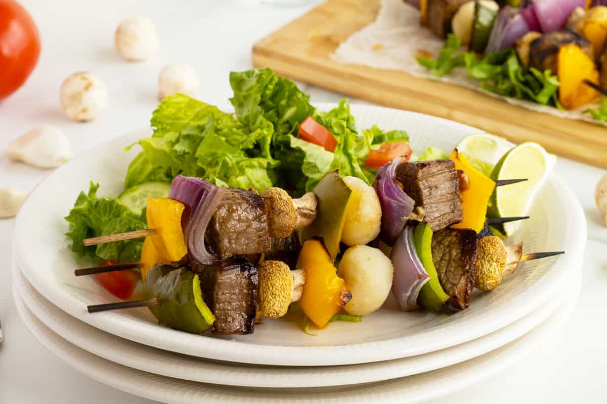 beef kabobs on skewers on a white plate