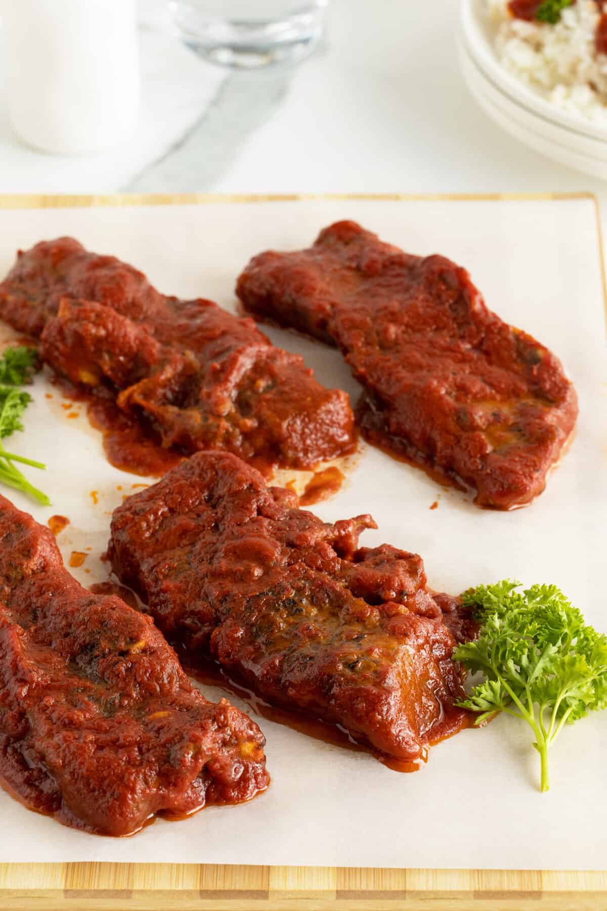 slow cooker short ribs on parchment paper with a sprig of parsley