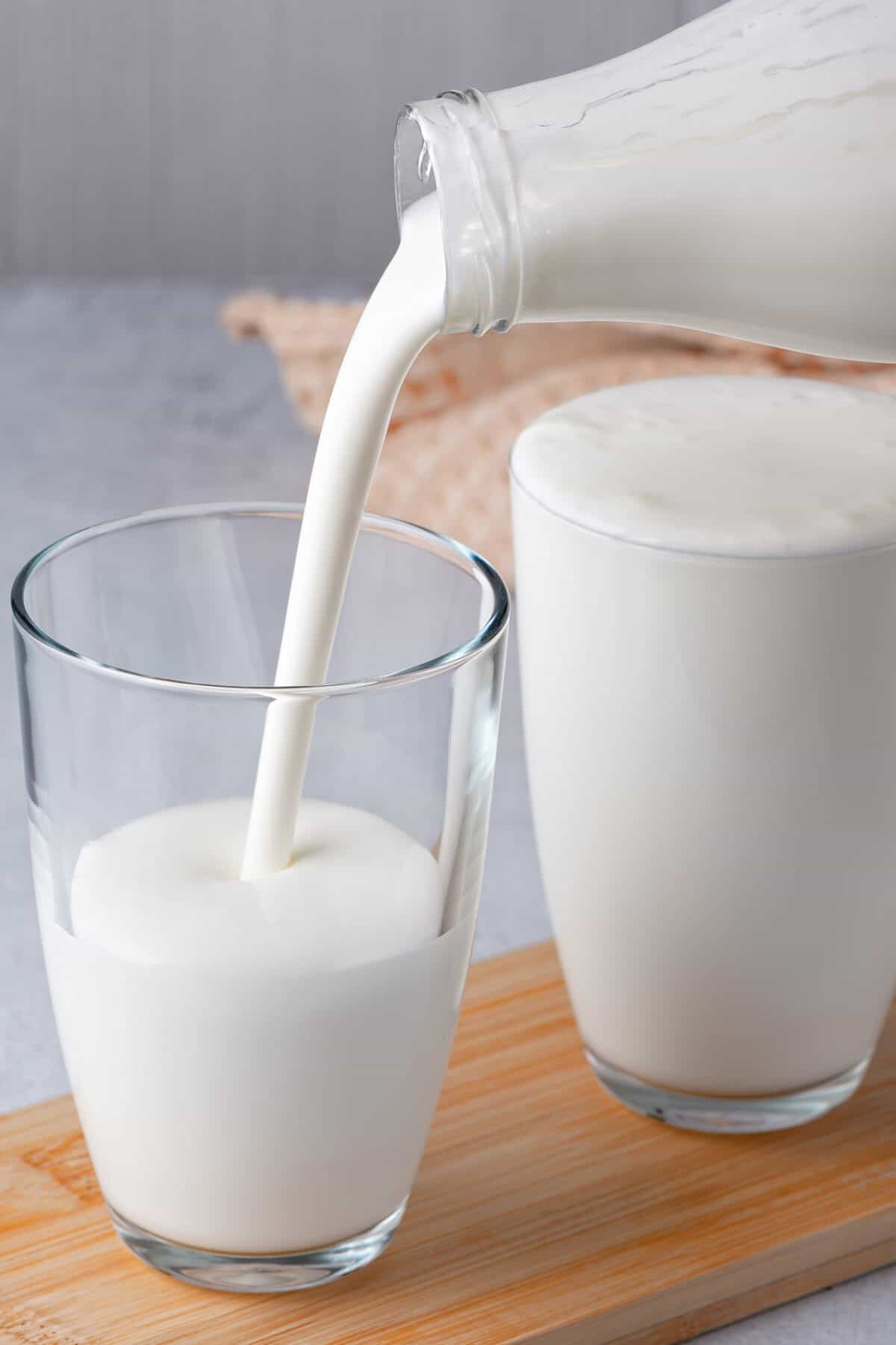 buttermilk being poured into a clear glass that is half full