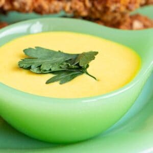 honey mustard in a green bowl with a leaf of parsley on top