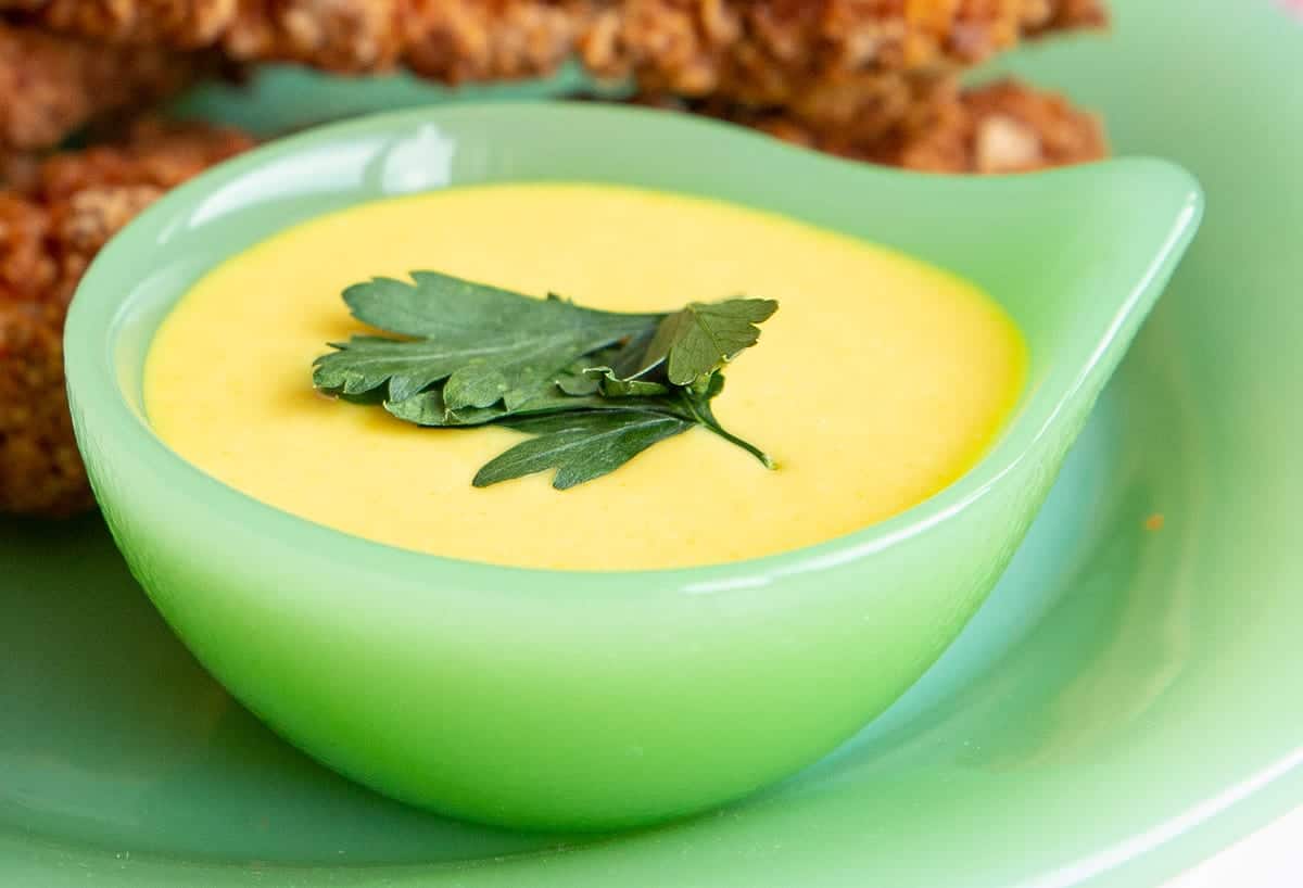 honey mustard in a green bowl with a leaf of parsley on top