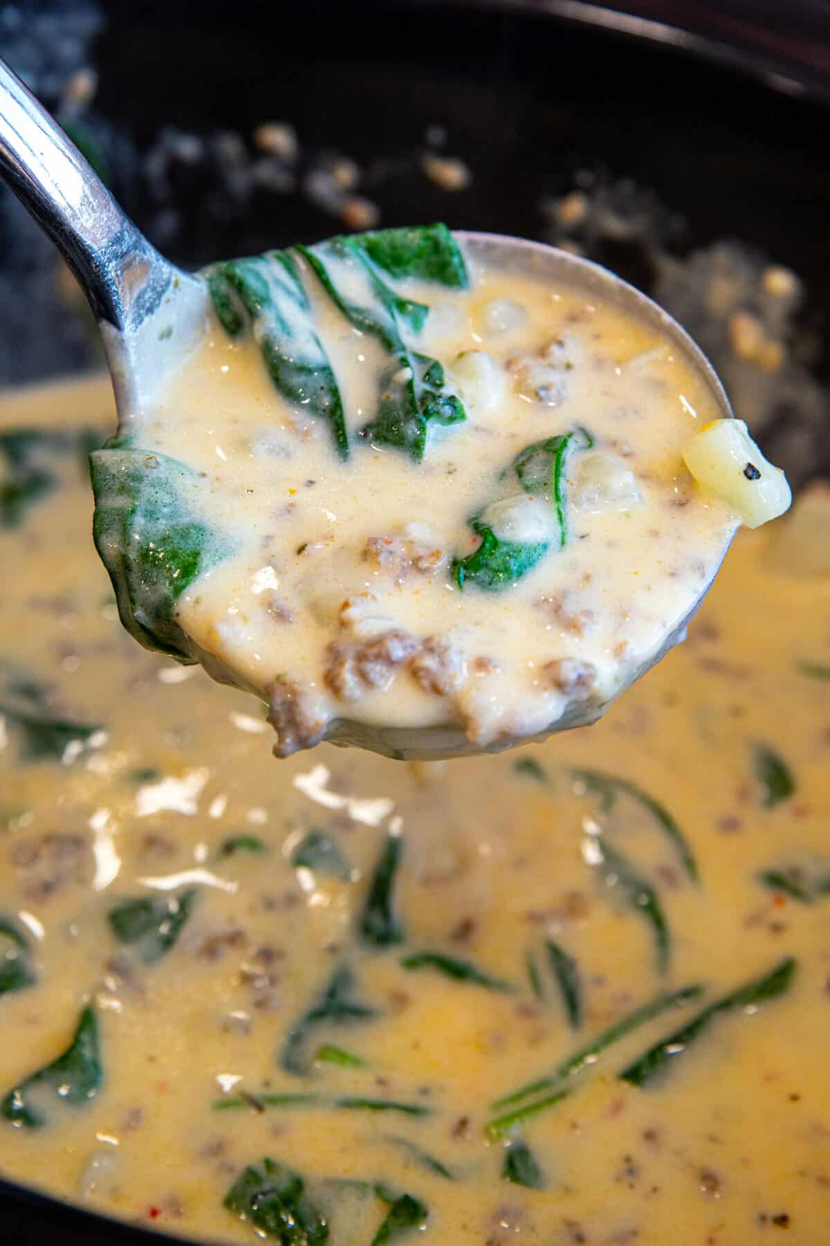 spinach and Italian sausage soup in a ladle