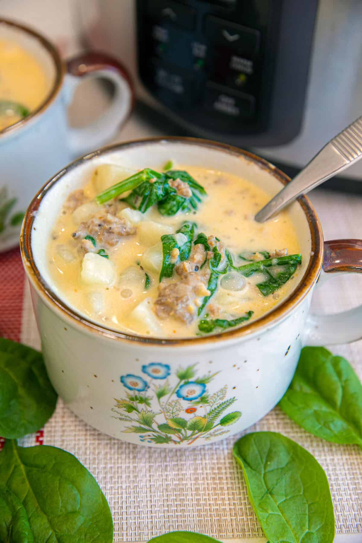 spinach and Italian sausage soup in a bowl with a spoon