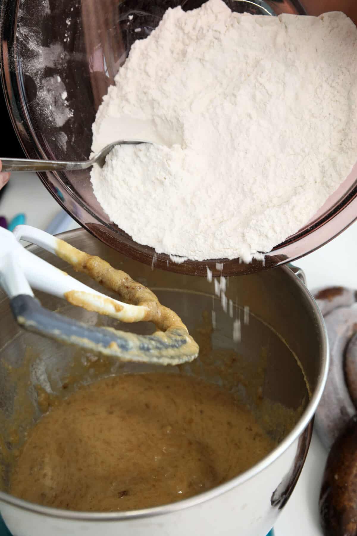 adding flour to a mixing bowl full of batter
