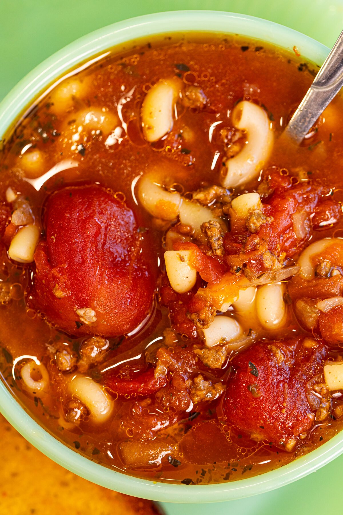 a jadeite bowl full of beef and tomato macaroni soup