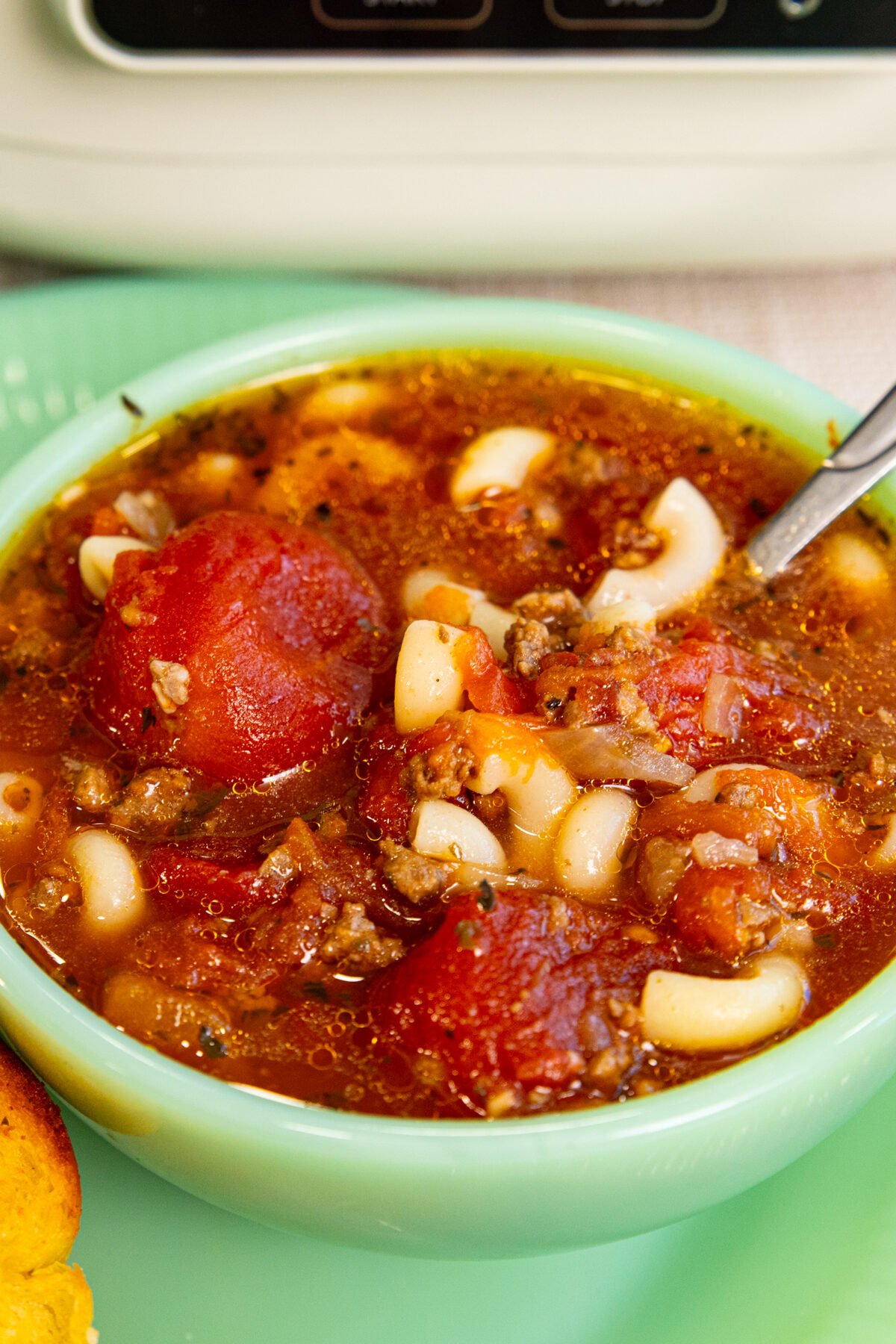 a jadeite bowl full of beef and tomato macaroni soup