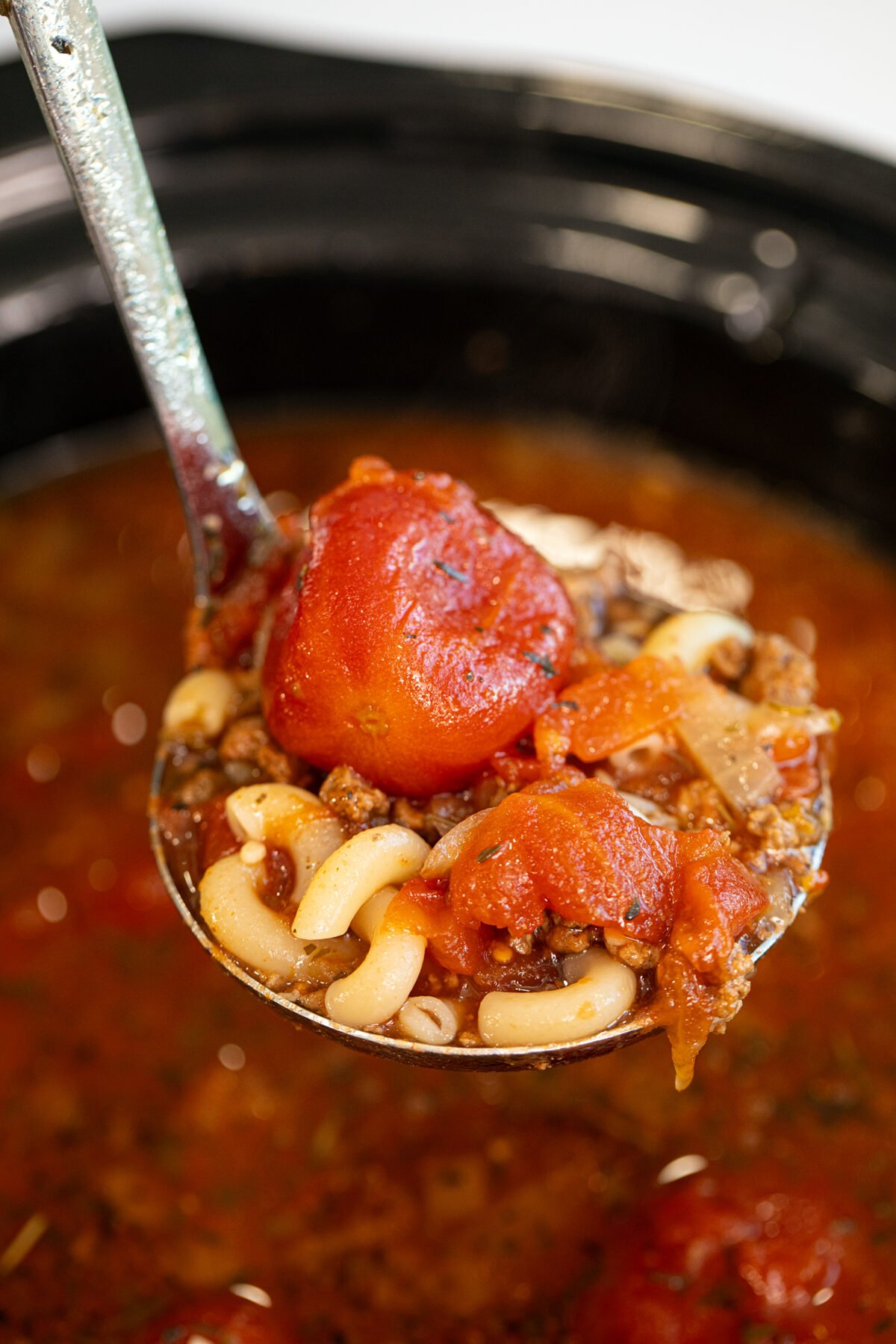 a ladle of beef and tomato macaroni soup