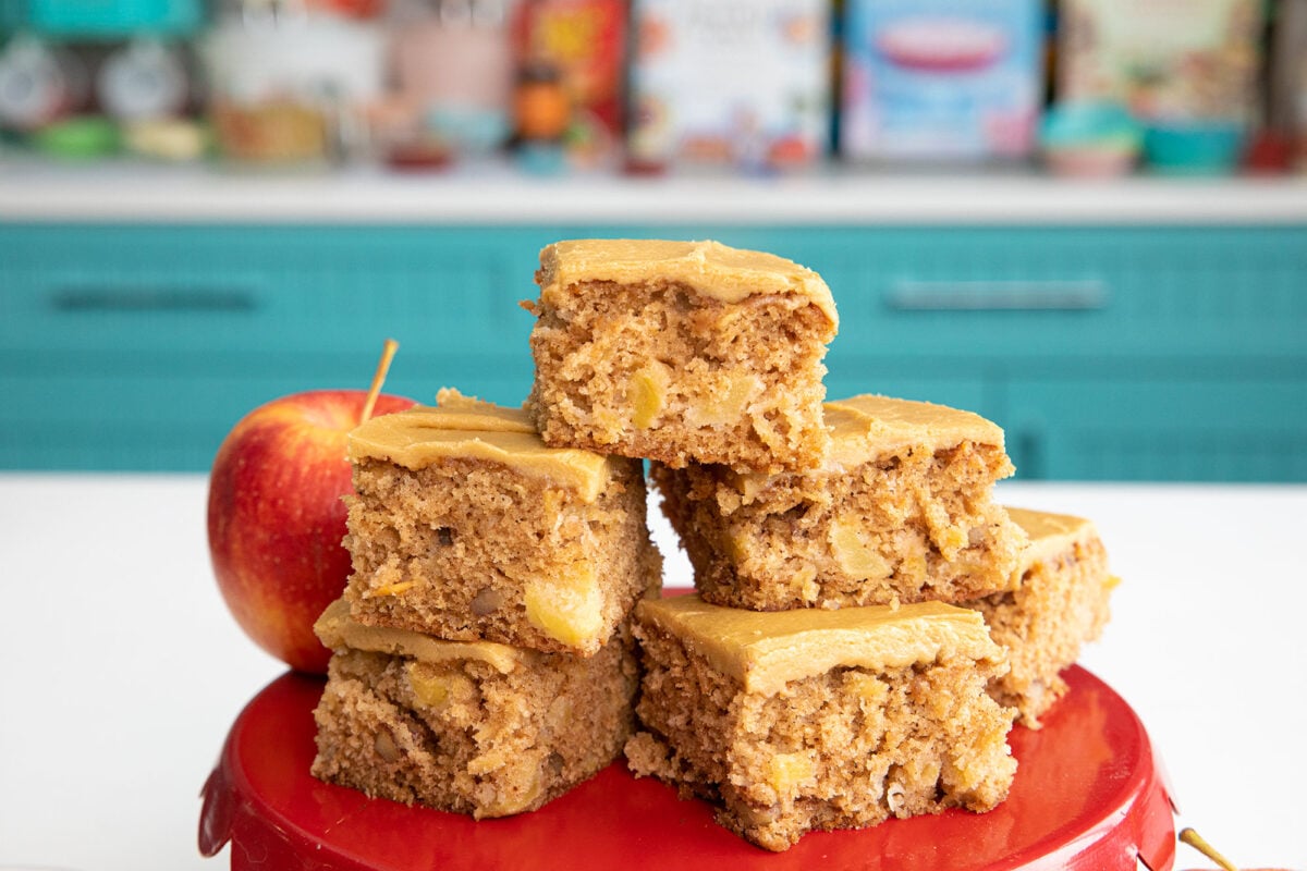 slices of frosted apple cake on a red platter