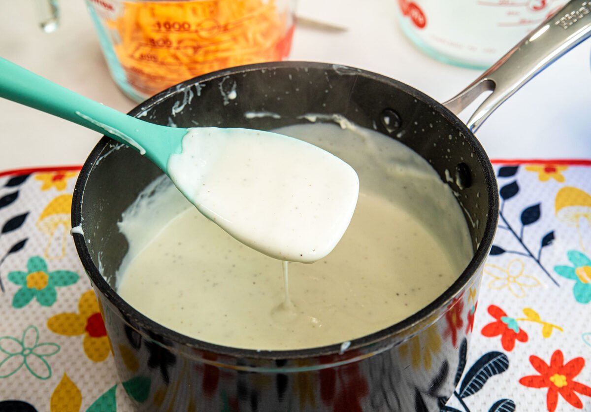 Béchamel sauce in a saucepan with a turquoise spoon