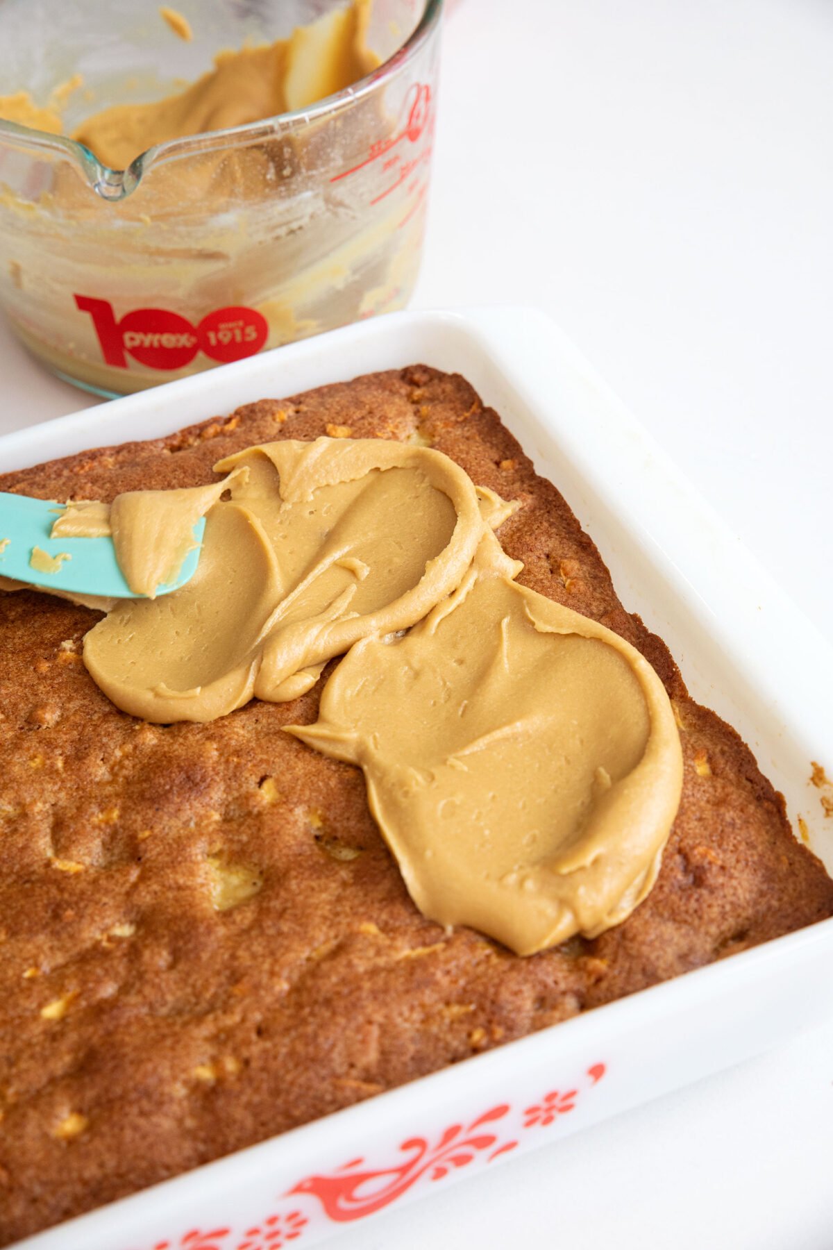 spreading brown sugar icing glaze on top of a cake using a spatula