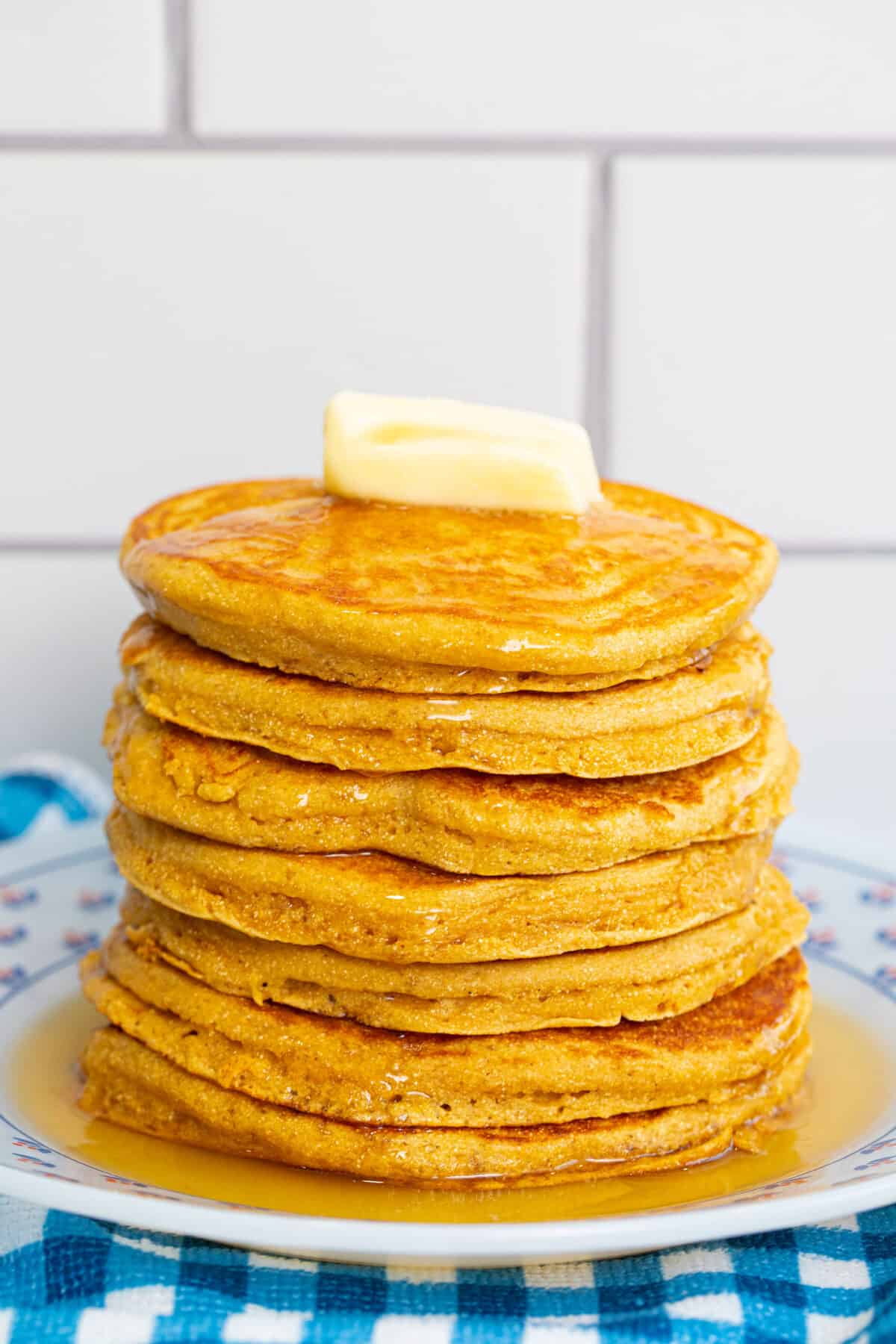 a stack of cornmeal pancakes with butter and maple syrup on top
