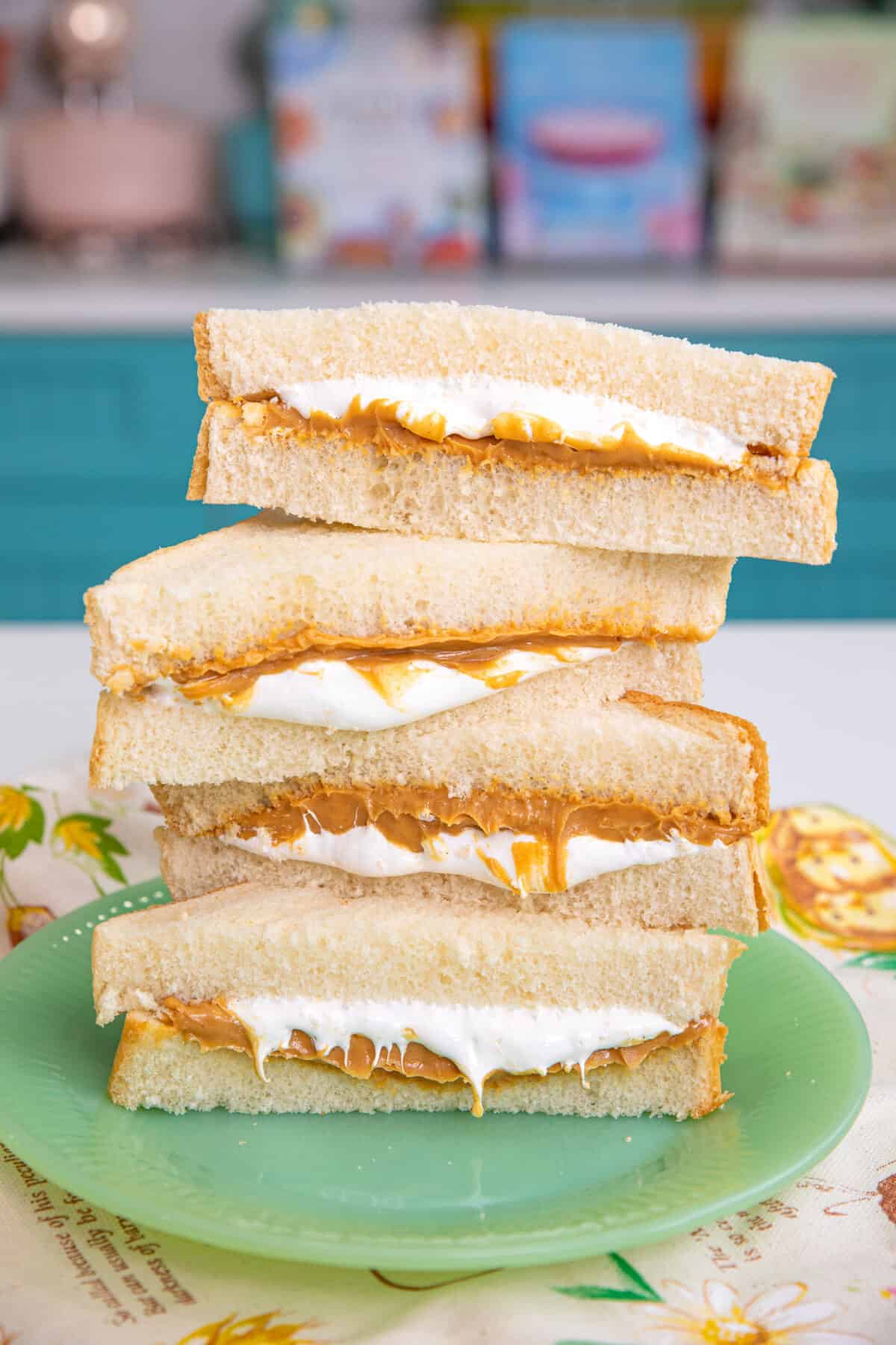 fluffernutter sandwich cut in half on a green plate stacked with peanut butter and marshmallow dripping out.