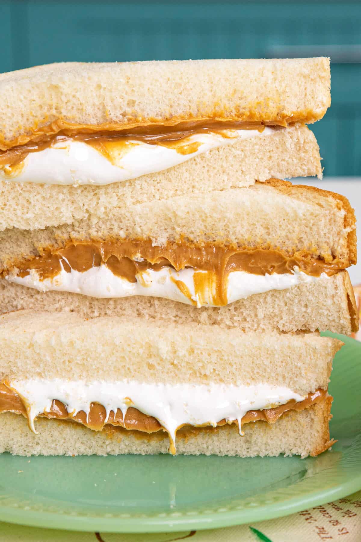 fluffernutter sandwich cut in half stacked with peanut butter and marshmallow dripping out.