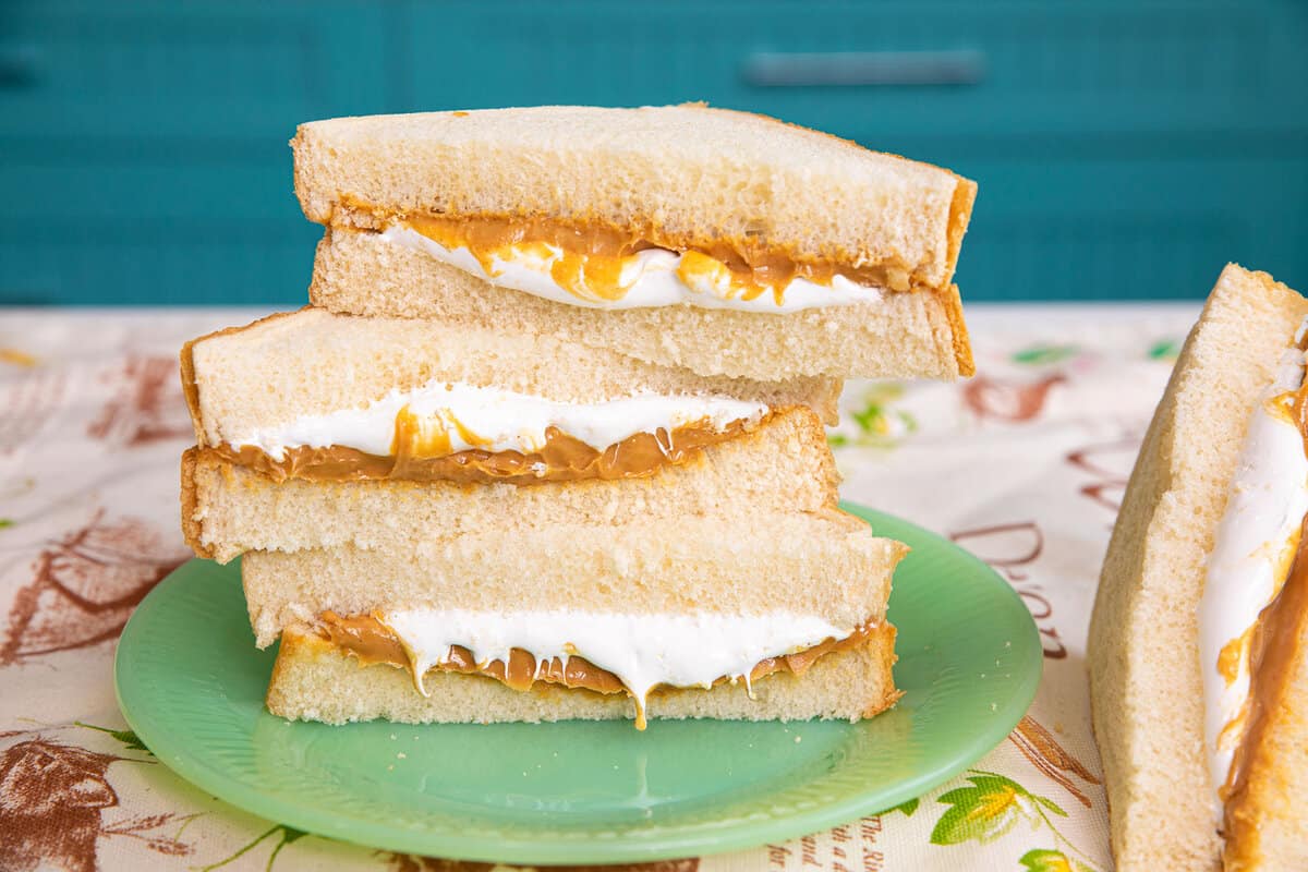 fluffernutter sandwich cut in half stacked with peanut butter and marshmallow dripping out.