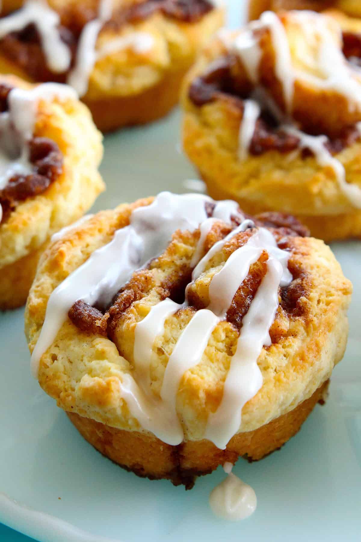 cinnamon rolls coated in buttery vanilla icing glaze on a plate (close-up)