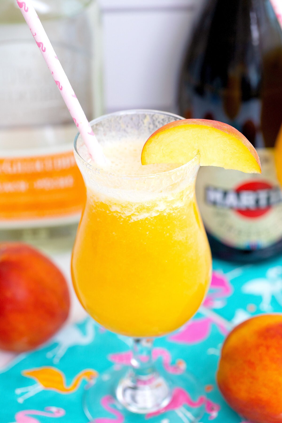 close-up of a peach bellini in a glass with the ingredients in the background