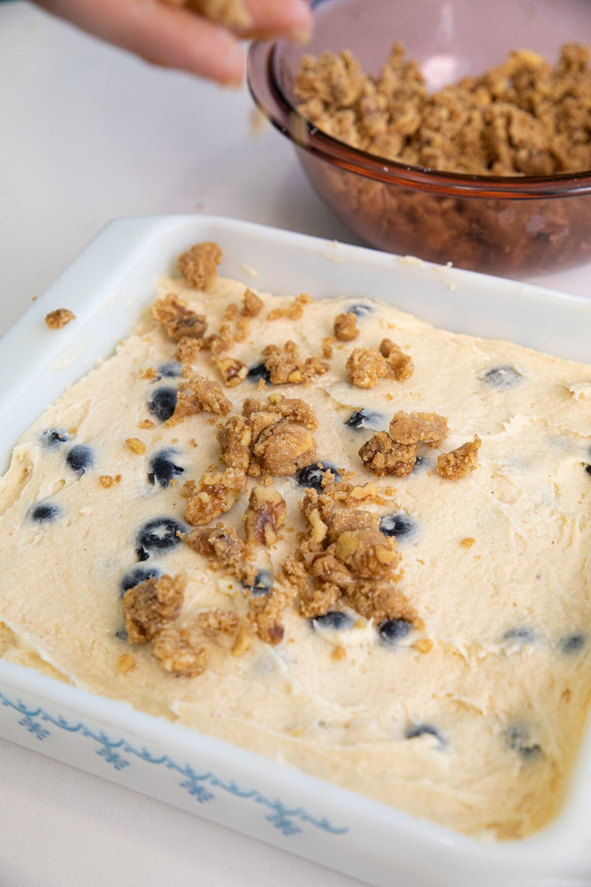 sprinkling streusel on top of  blueberry coffee cake batter