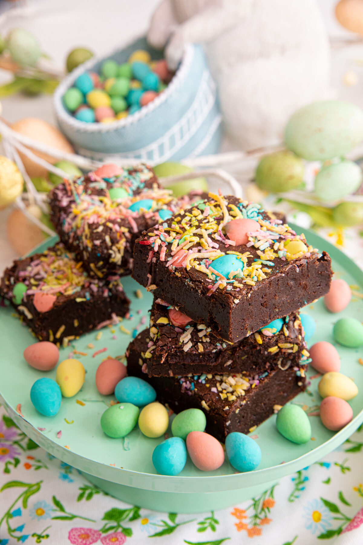 Easter brownies stacked on a stand surrounded by mini eggs